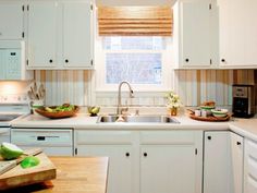 a kitchen with white cabinets and wooden counter tops is pictured in this image, there are two bowls of fruit on the counter