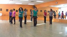 a group of young women standing on top of a wooden floor in a dance studio