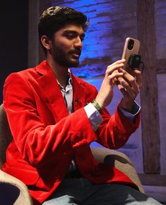 a man sitting in a chair holding up a cell phone