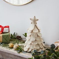 a white christmas tree sitting on top of a table next to a mirror and presents