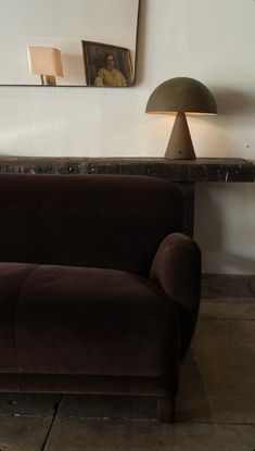 a brown couch sitting next to a table with a lamp on it's side