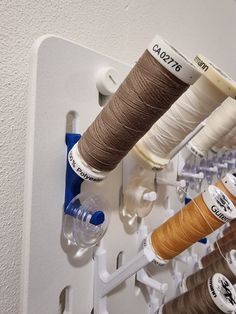 several spools of thread are hanging on the wall