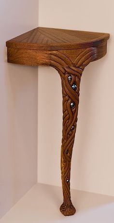 a wooden table with an intricate design on it's top and bottom edge, against a white wall