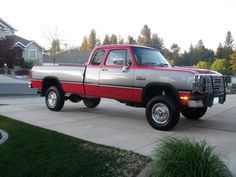 a red and silver truck parked on the side of a road in front of a house