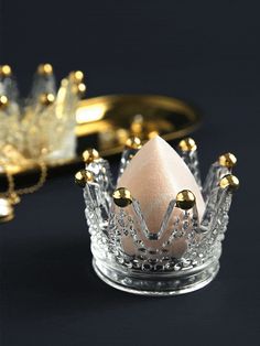 a gold and crystal crown ring on a black surface