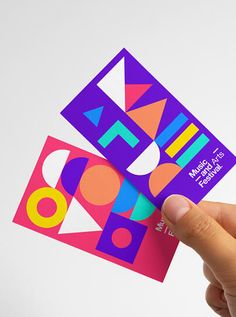 a person holding up a business card with the word art on it and colorful shapes