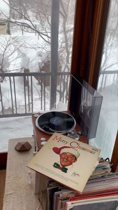 a record player sitting on top of a table next to a window with snow outside