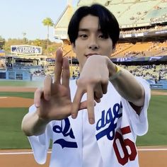 a baseball player is making the peace sign with his hand while standing in front of an empty stadium