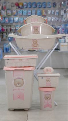 three white and pink containers with teddy bears on them in front of shelves filled with baby products