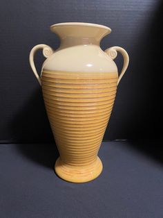 a yellow and white vase sitting on top of a black table next to a wall