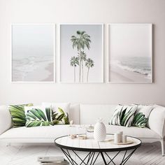 three paintings hang on the wall above a white couch and coffee table in a living room