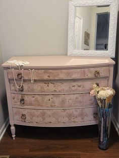 an old dresser with flowers and a mirror