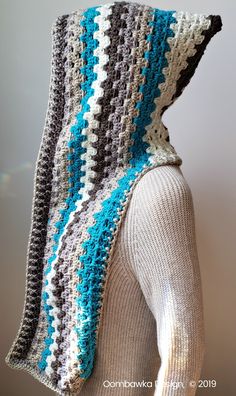 a woman is wearing a crocheted shawl with blue and gray stripes on it