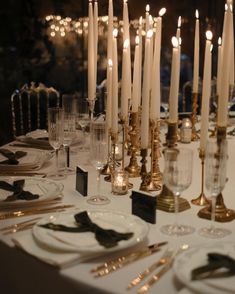 there are many candles that are on the table with plates and silverware in front of them