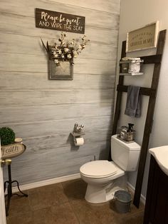 a white toilet sitting in a bathroom next to a sink and wooden ladder with flowers on it