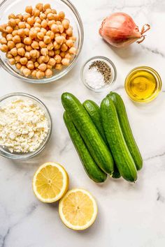 cucumbers, lemons, chickpeas and other ingredients laid out on a marble counter top