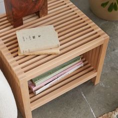 a wooden table with books on it next to a potted plant and a vase