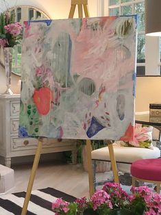 an easel is holding up a painting in the middle of a room filled with flowers