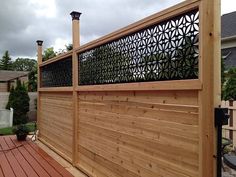 a wooden fence with decorative iron work on the top and bottom panels, along with a wood deck