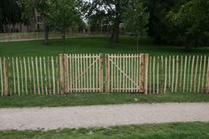 a wooden fence in the middle of a grassy area with trees and grass behind it