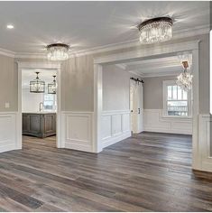 an empty living room with wood floors and chandeliers