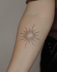 a woman's arm with a small sun tattoo on the back of her left arm