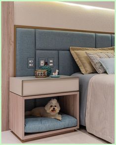 a small white dog laying on top of a bed under a night stand next to a nightstand