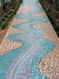 a long walkway with blue and white tiles on the ground in front of some trees