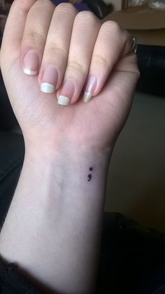 a woman's hand with a small black dot on the middle of her wrist