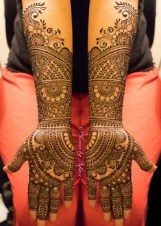 two hands with henna tattoos on them, one is showing off the intricate design