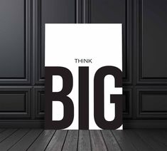 a black and white poster with the words think big on it in front of a wooden floor