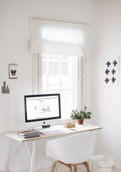 a white desk with a computer on it in front of a window and potted plant