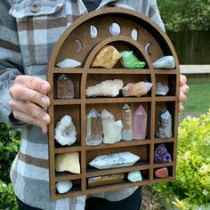 a person holding a wooden display case with various rocks and crystals in the middle,