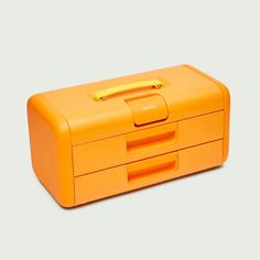 an orange lunch box sitting on top of a white table next to a yellow object