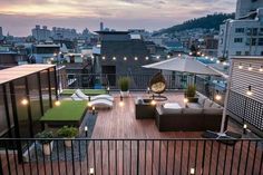 an outdoor living area with patio furniture and lights on the roof top, overlooking cityscape