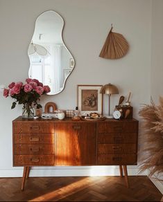 a wooden dresser topped with lots of drawers and vases next to a large mirror