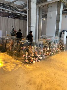 two people sitting at a counter with flowers in the middle and on the other side