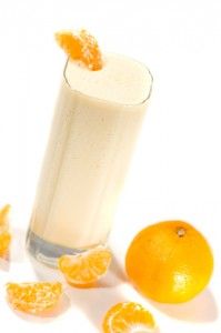 an orange is falling into a glass of milk