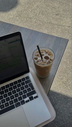 an open laptop computer sitting on top of a wooden table next to a cup of coffee