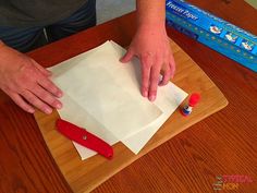 a person cutting paper on top of a wooden table