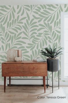 a wooden table sitting next to a plant on top of a hard wood floor