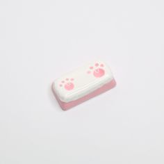 a pink and white toy with paw prints on it's side sitting on a white surface