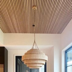 a chandelier hanging from the ceiling in a room with wood slats on the ceiling