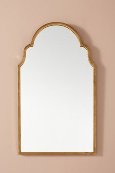 a gold framed mirror on a pink wall