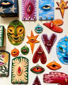 many colorful masks are arranged on a table top, including one with an evil face