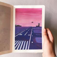 a person holding up an open book with watercolors on it and the pages are empty