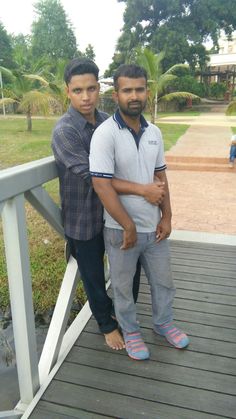 two young men standing on a wooden deck next to each other with their arms around one another