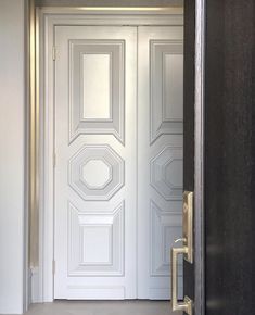 an open door in a white room with black and gold trim on the front doors