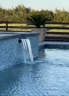 an outdoor pool with a waterfall running into it