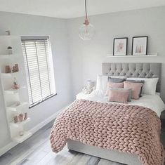 a bedroom with white walls and pink bedding in the center, along with shelving on the wall